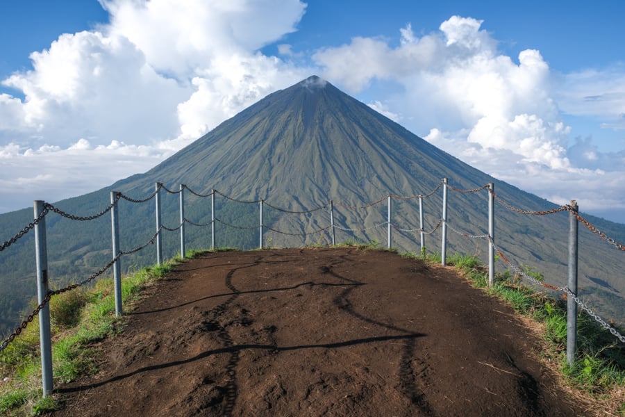Флорес: Життя біля вулкана Місцевий чоловік на мотоциклі на тлі вулкана Інеріє, Флорес, Індонезія.