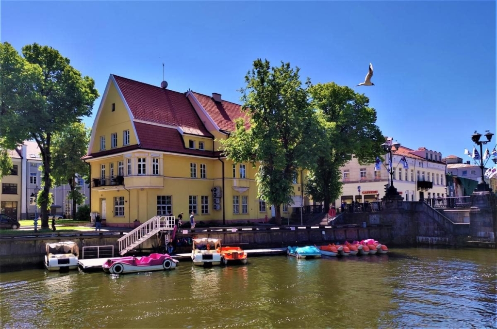 Морська історія Клайпеди Вид на історичний порт Клайпеди з кораблями та човнами, що підкреслює морську історію міста.